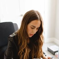 A woman seated at a desk, writing in a calendar.