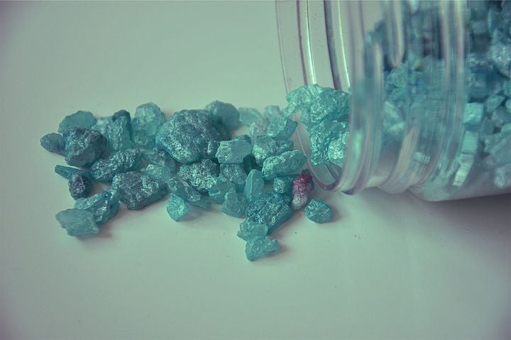 Blue rocks spilling out of a glass jar