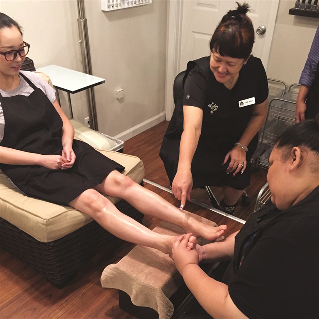 A La Mer Nail Institute instructor advises a student on proper technique.