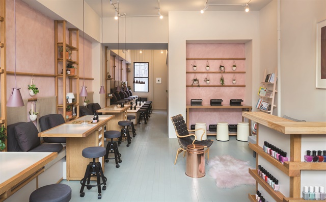 The salon interior hosts an abundance of plants and fresh flowers along the sides of each station, and a rack of thought-provoking books.