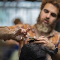 A barber inside his shop works on a client.